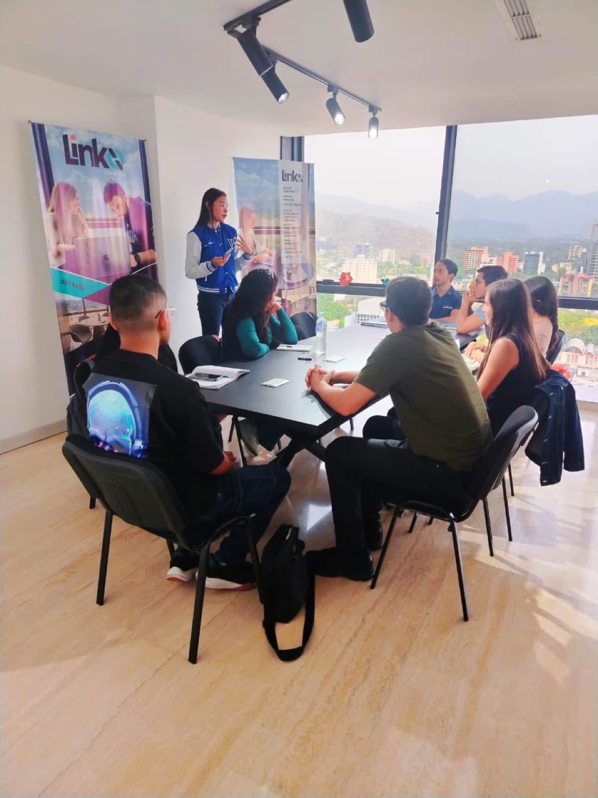 Sala de reuniones con equipo de trabajo alrededor de mesa y branding Linko en pantalla